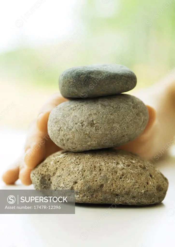 Hand touching stack of pebbles