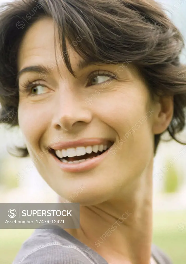 Woman smiling over shoulder, close-up of head, portrait