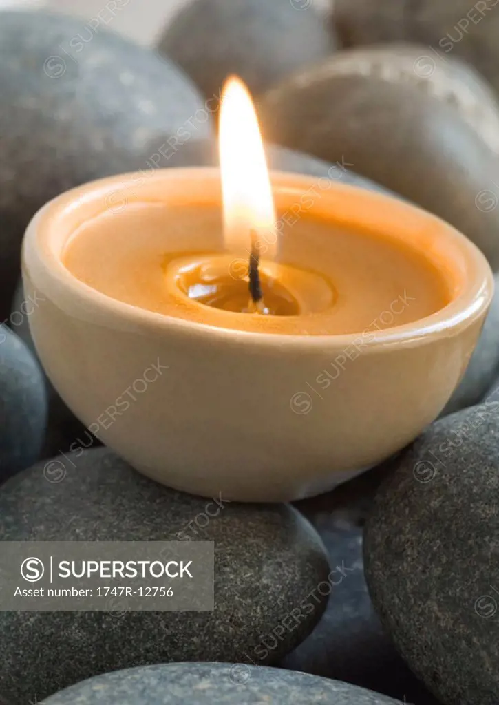 Lit candle on stones