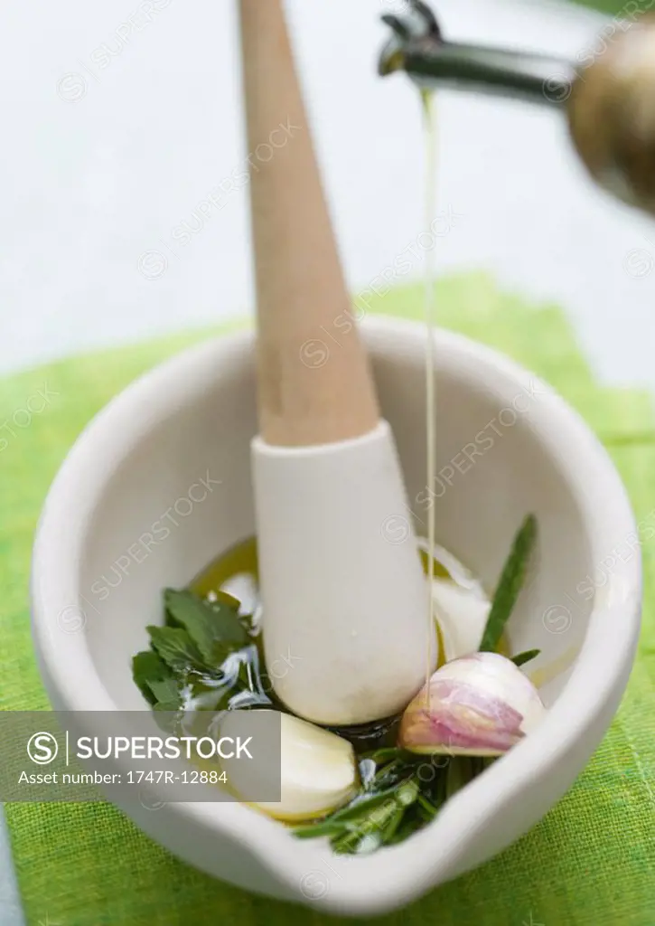 Mortar and pestle with herbs, olive oil and garlic