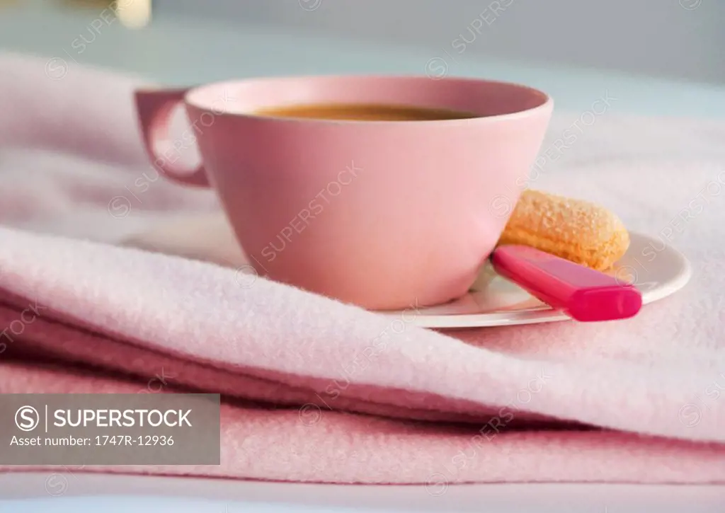 Cup of coffee on saucer with spoon and ladyfinger cookie