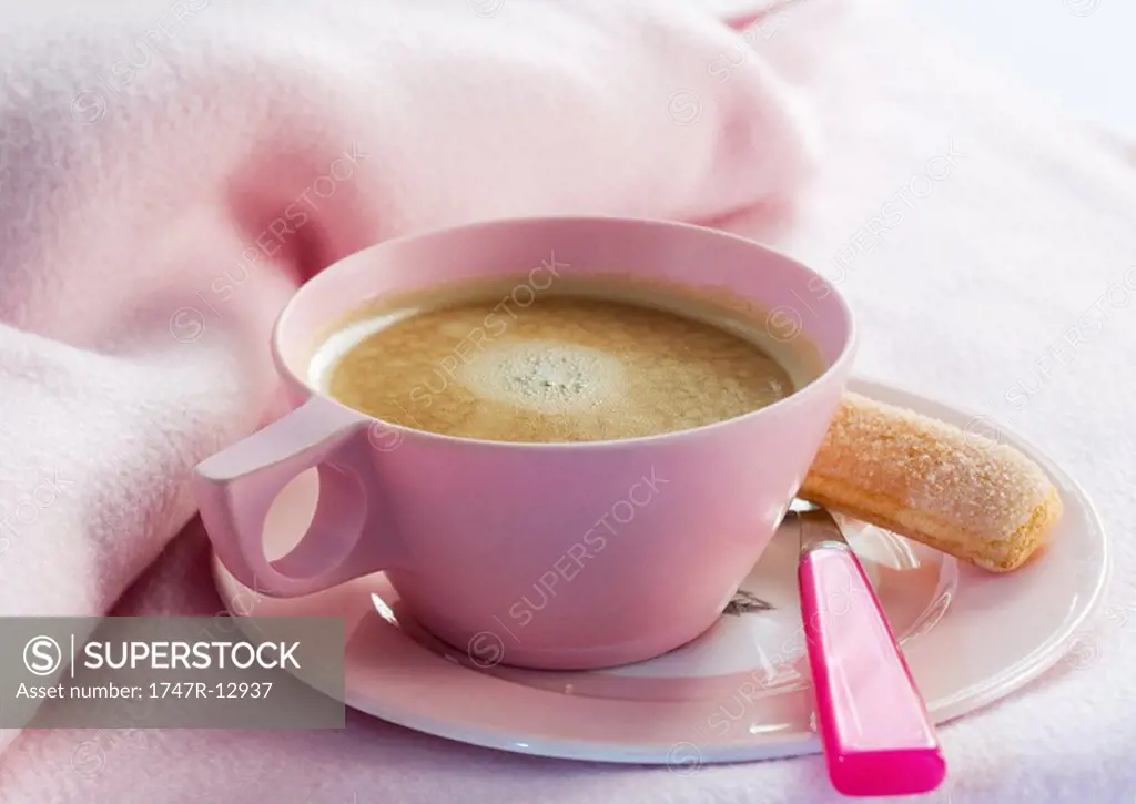 Cup of coffee on saucer with spoon and ladyfinger cookie