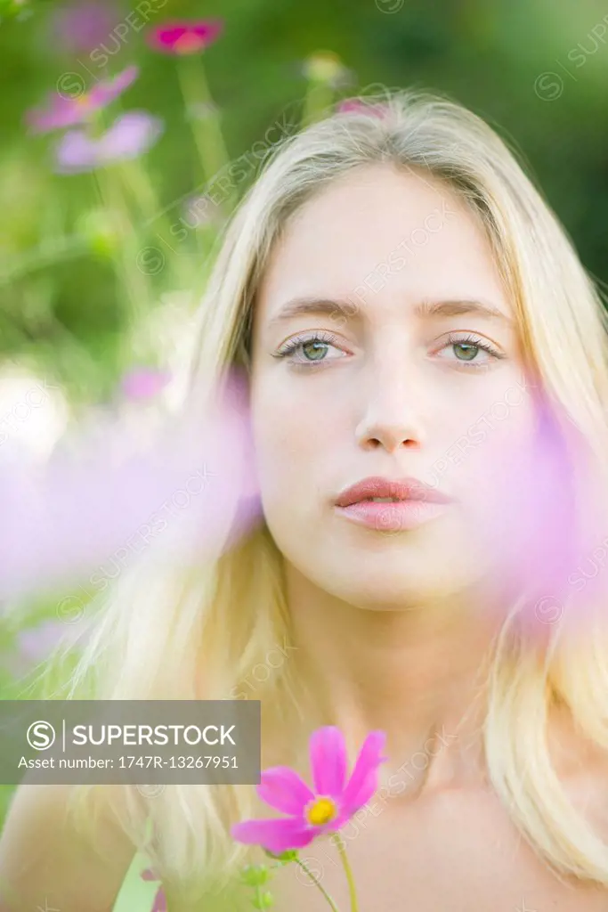 Young woman among cosmos flowers, portrait