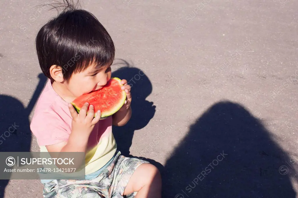 Little boy eating watermelon outdoors