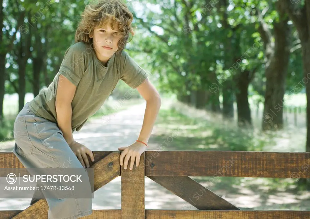 Boy climbing fence, looking at camera