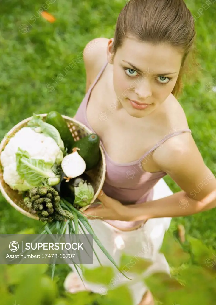 Woman holding basket of fresh vegetables, high angle view