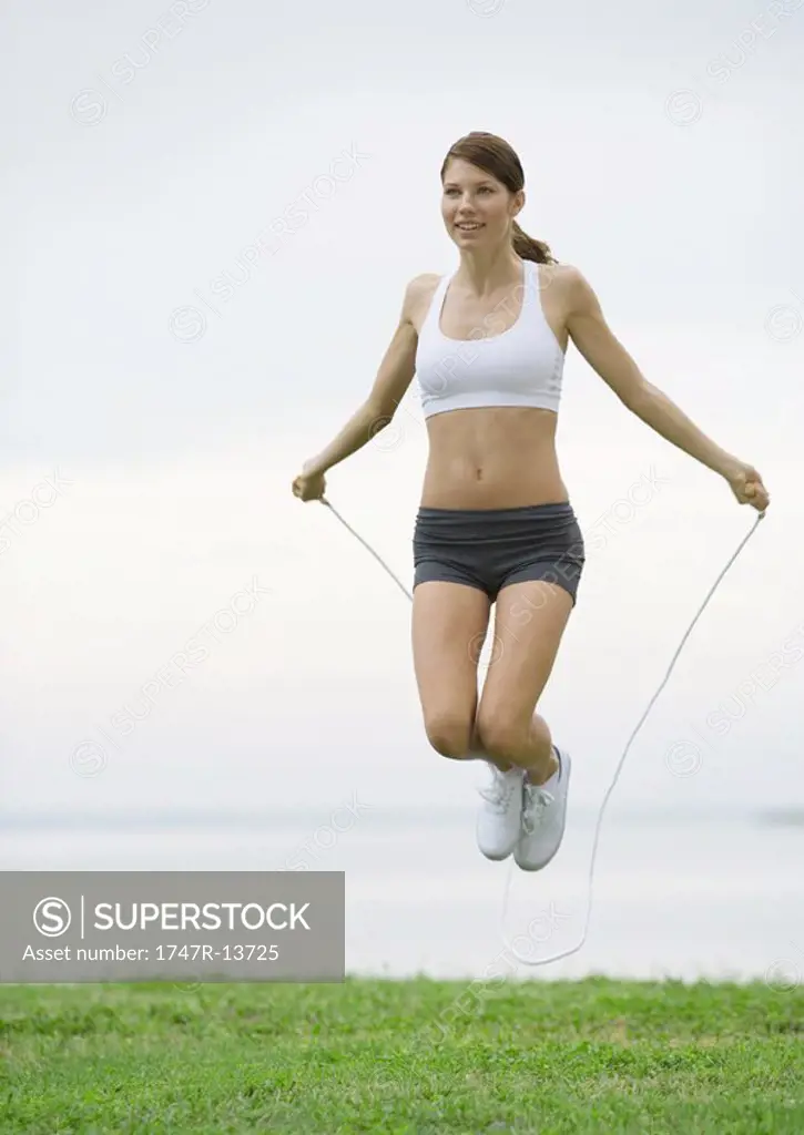 Young woman jumping rope by lakeside