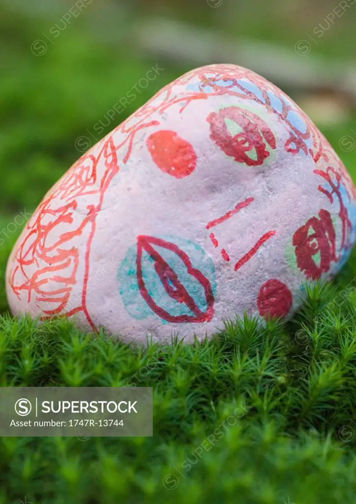 Stone decorated with face, lying on ground