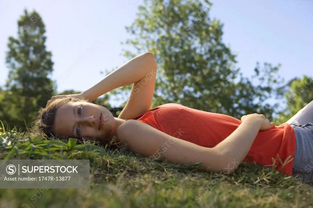 Young woman lying on back in grass, portrait