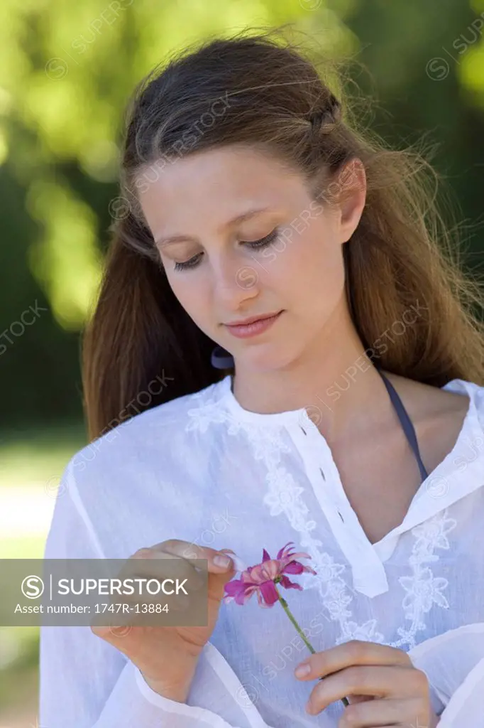 Young woman plucking petals from flower