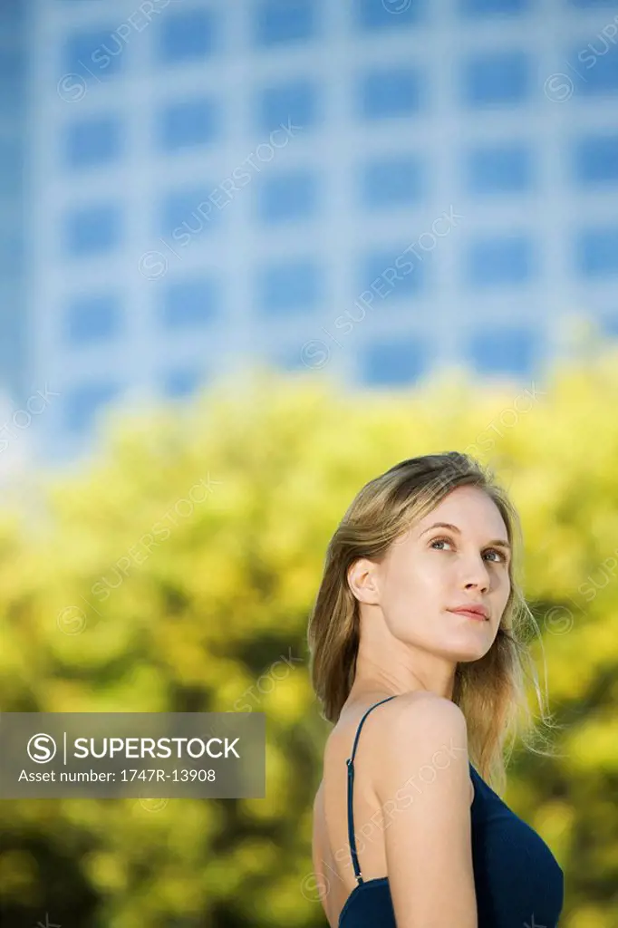 Woman outdoors, looking up dreamily, portrait