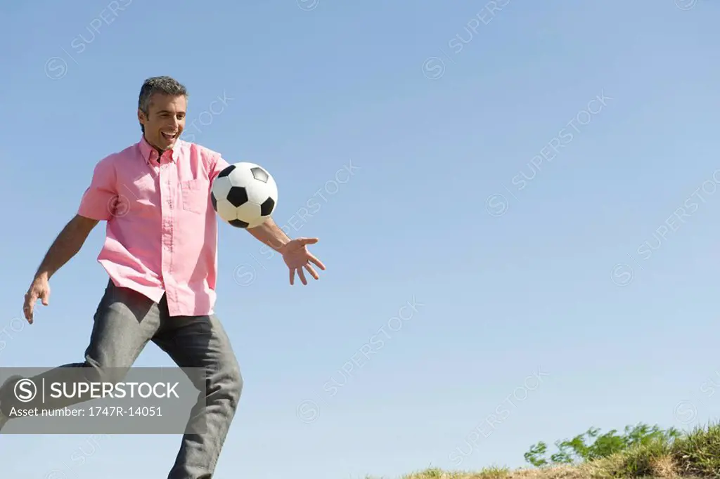 Man playing with soccer ball outdoors, smiling