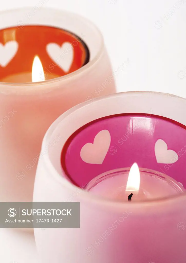 Lit candles in candleholder with heart pattern