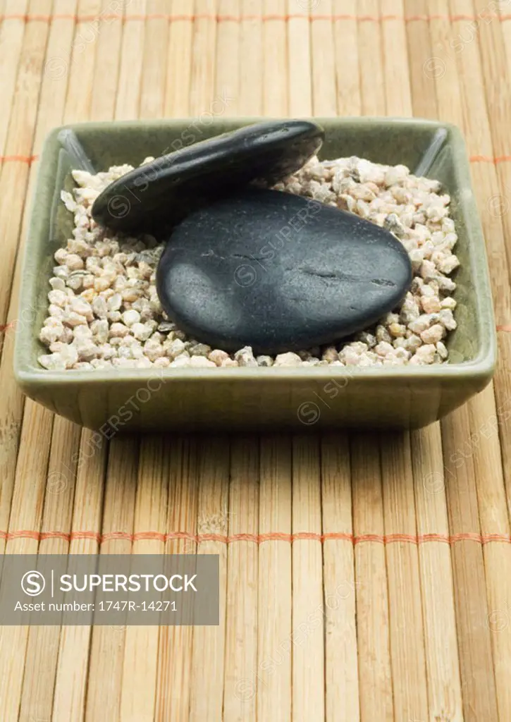 Square dish containing gravel and black stones