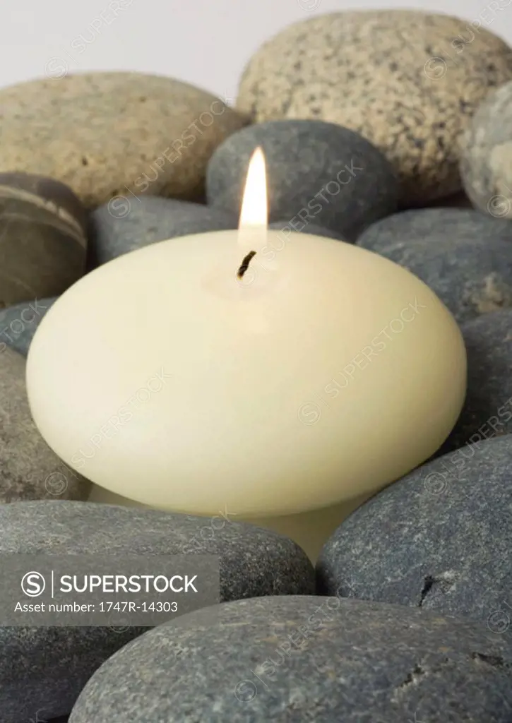 Candle burning, on stones