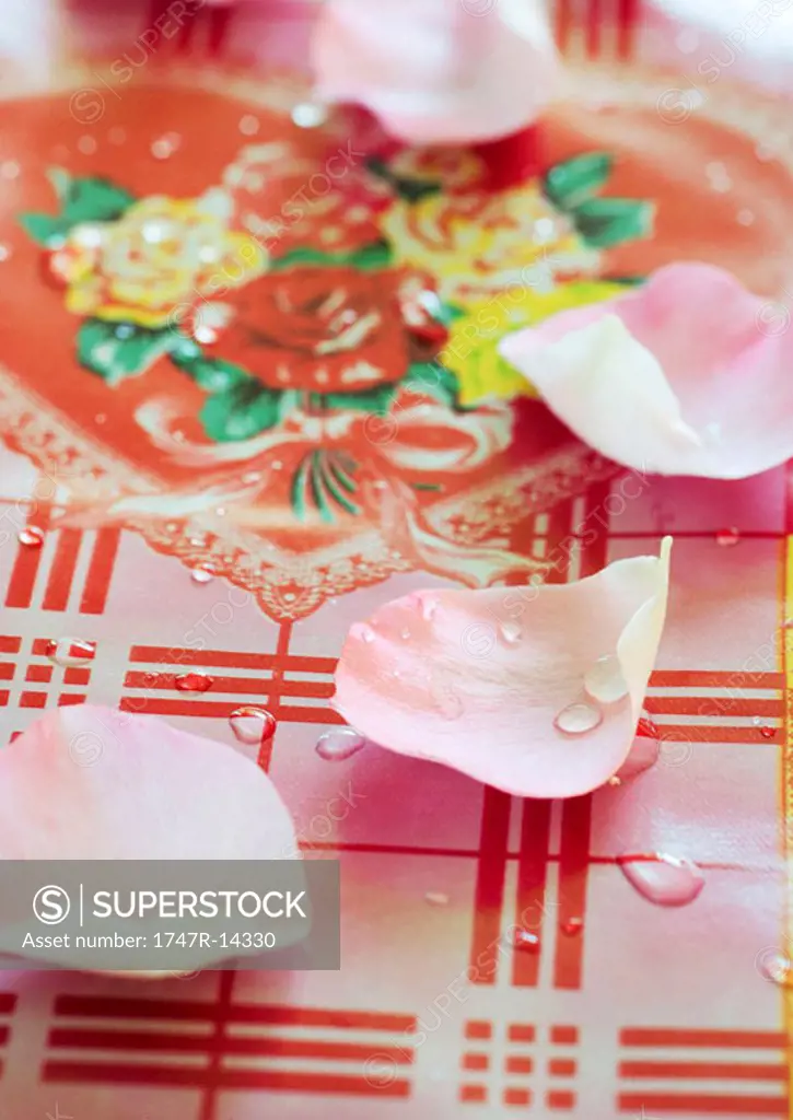 Rose petals and drops of water on decorative tablecloth