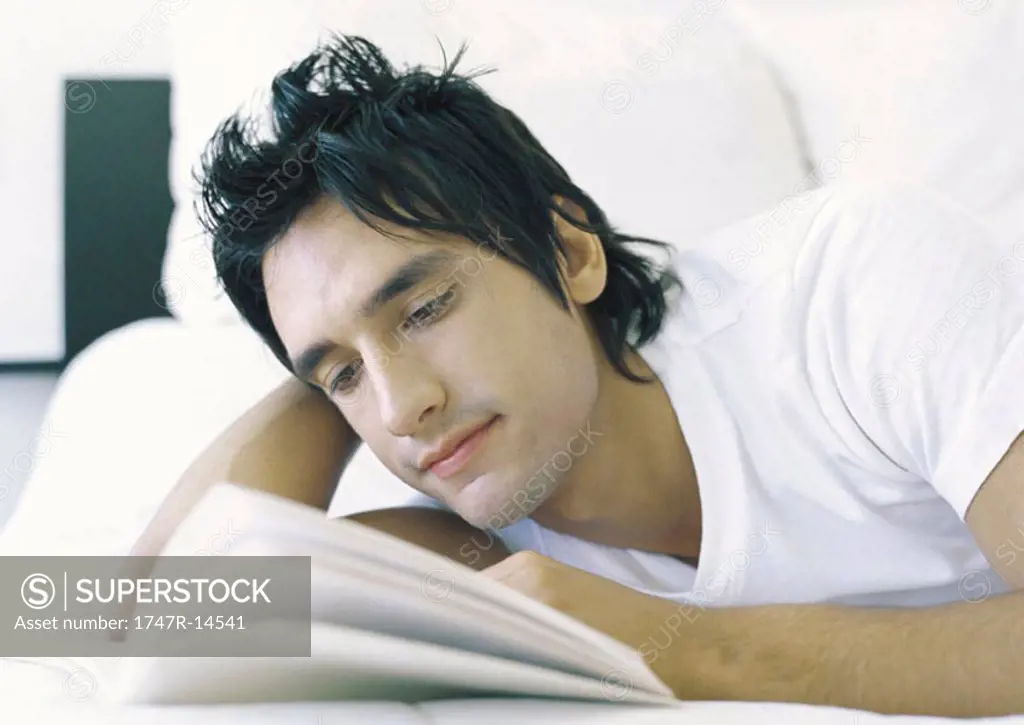 Man lying in bed, reading