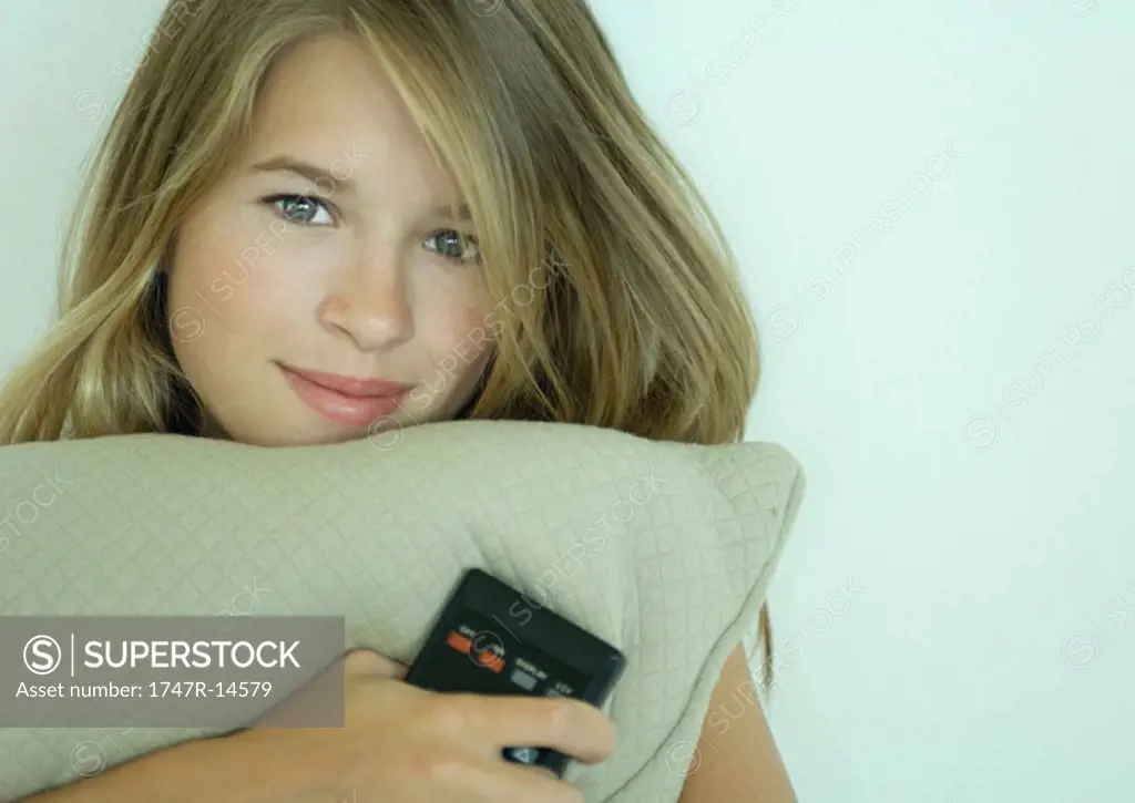 Woman holding cushion and remote control