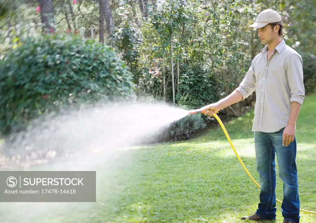 Man doing yardwork, using garden hose