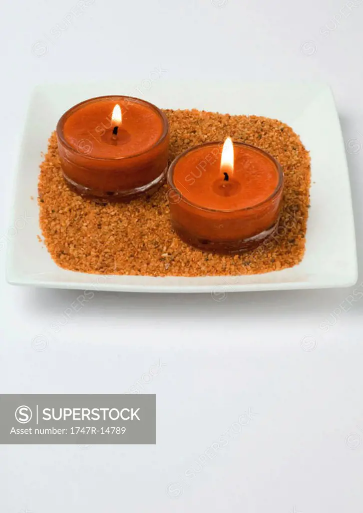 Candles on sand in square dish