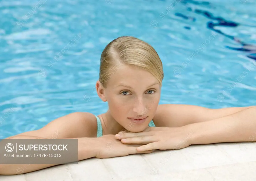 Young woman resting head on edge of pool