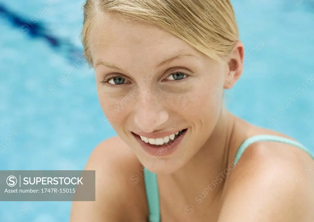 Young woman smiling, portrait, pool in background