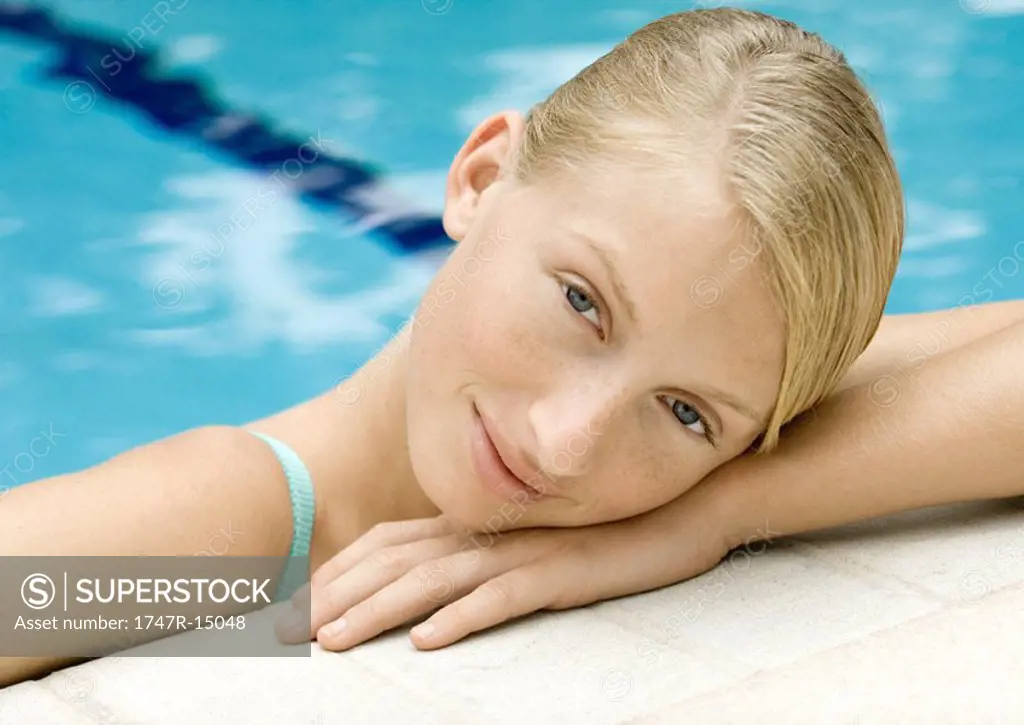Young woman resting head on edge of pool