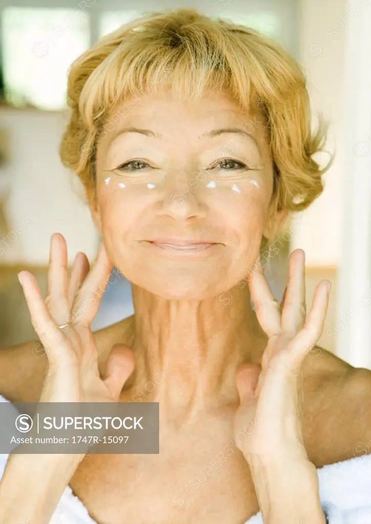 Senior woman applying moisturizer