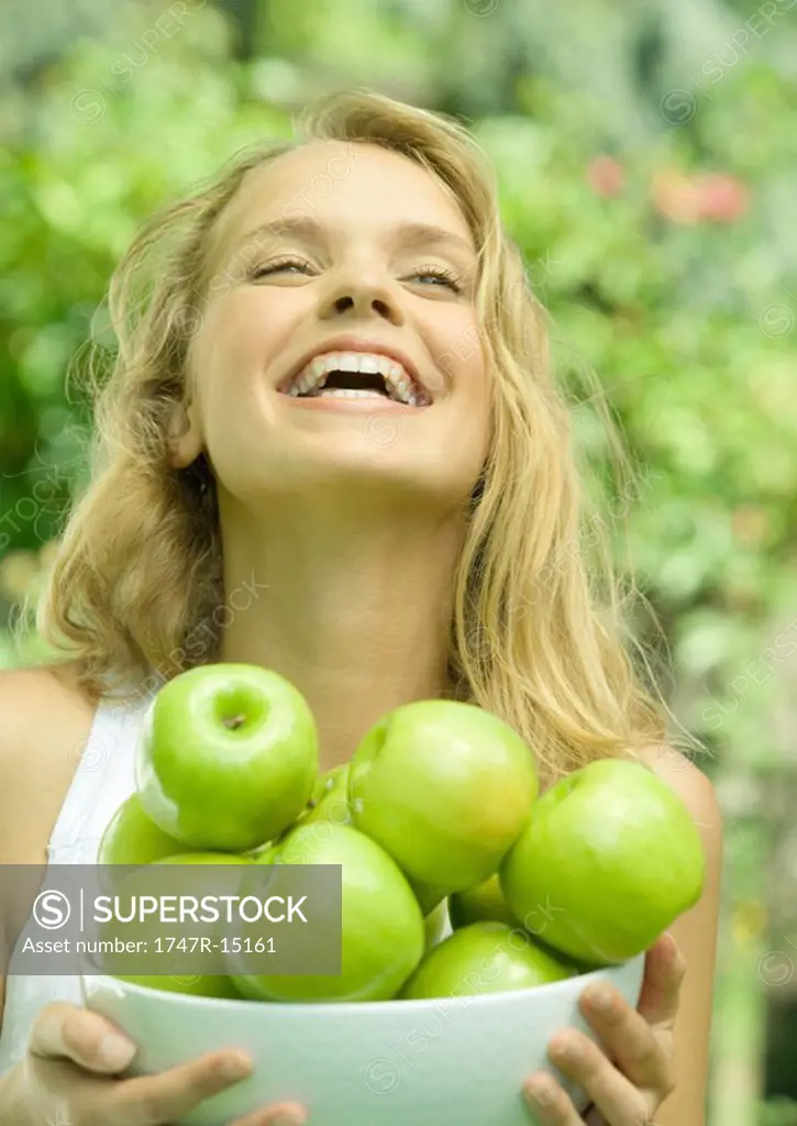 Woman holding bowl of apples, laughing