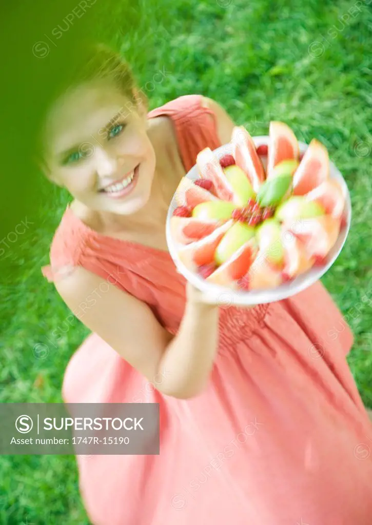 Woman holding up plate of fruit slices