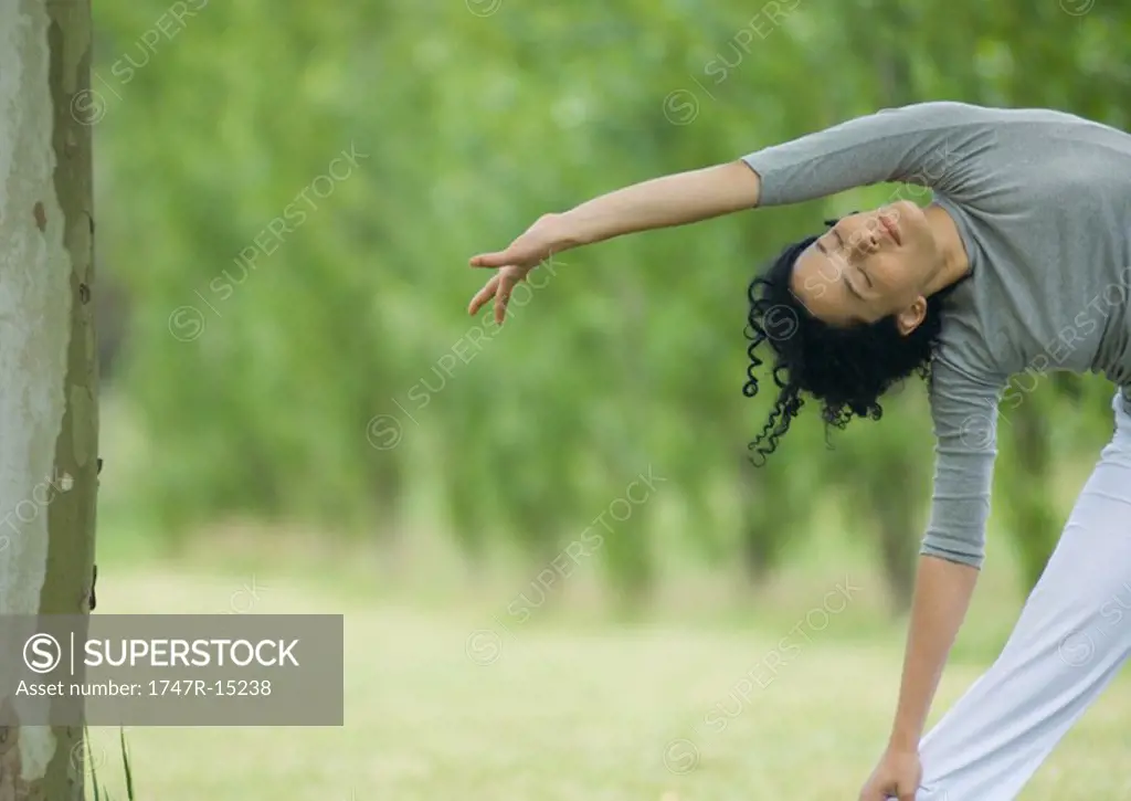Young woman doing side stretch outdoors