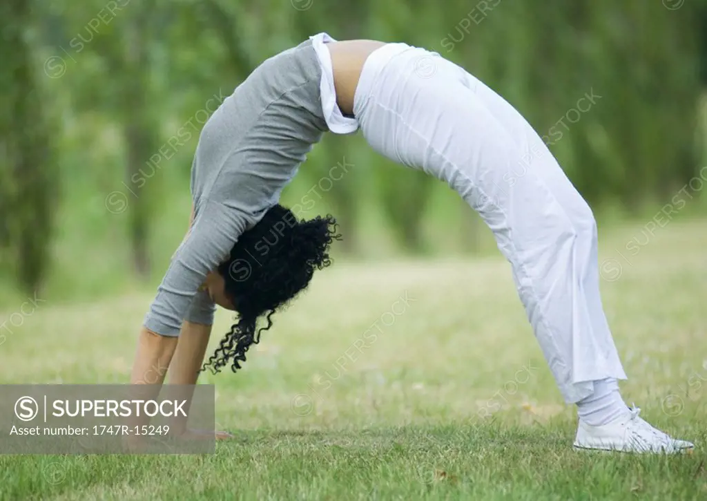 Young woman doing bridge on grass