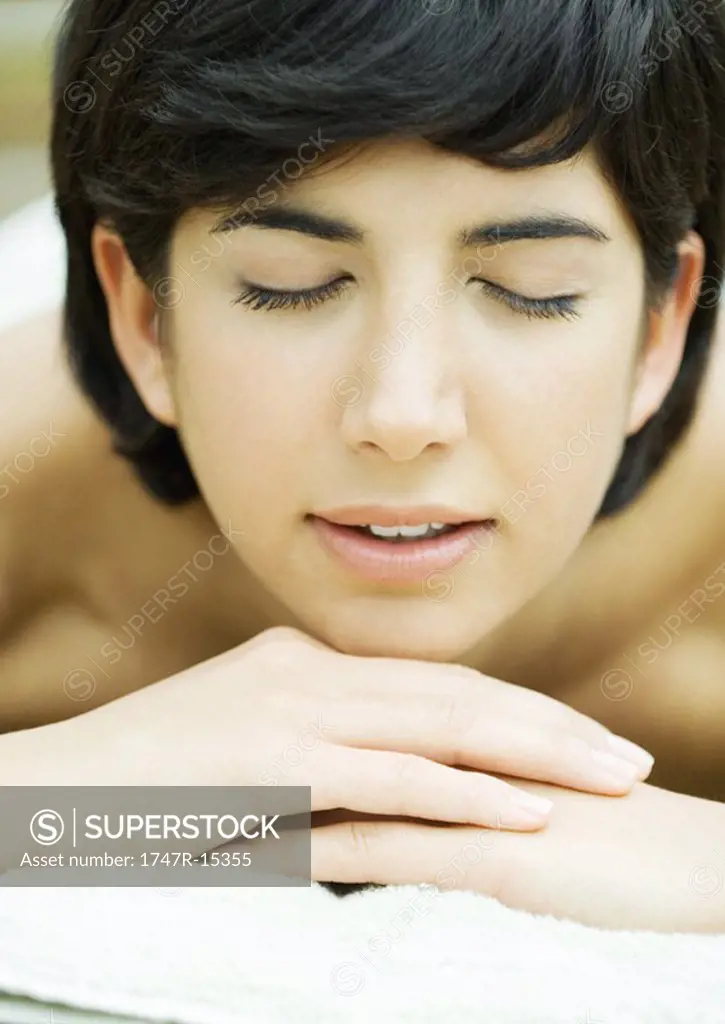 Woman lying with head on hands, eyes closed