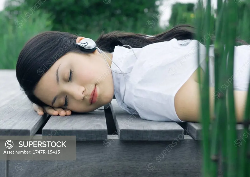 Woman lying on deck, listening to headphones