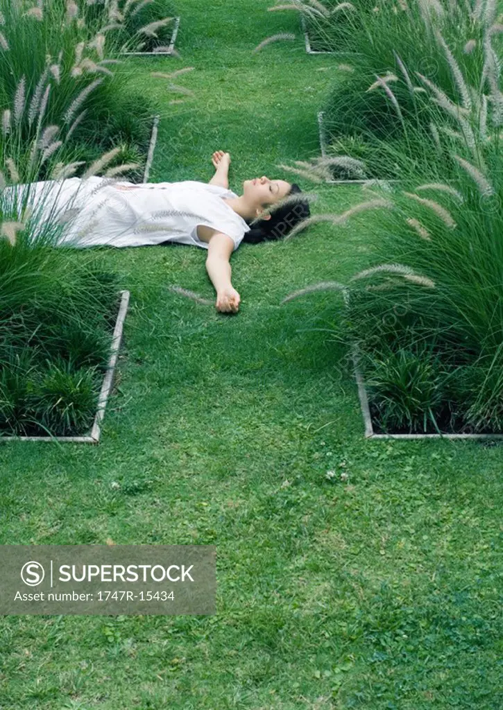 Woman lying on grass in ornamental garden