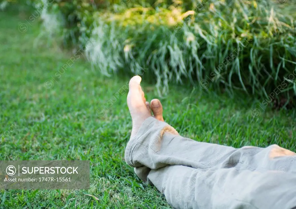 Man´s legs on grass, barefoot, knee down