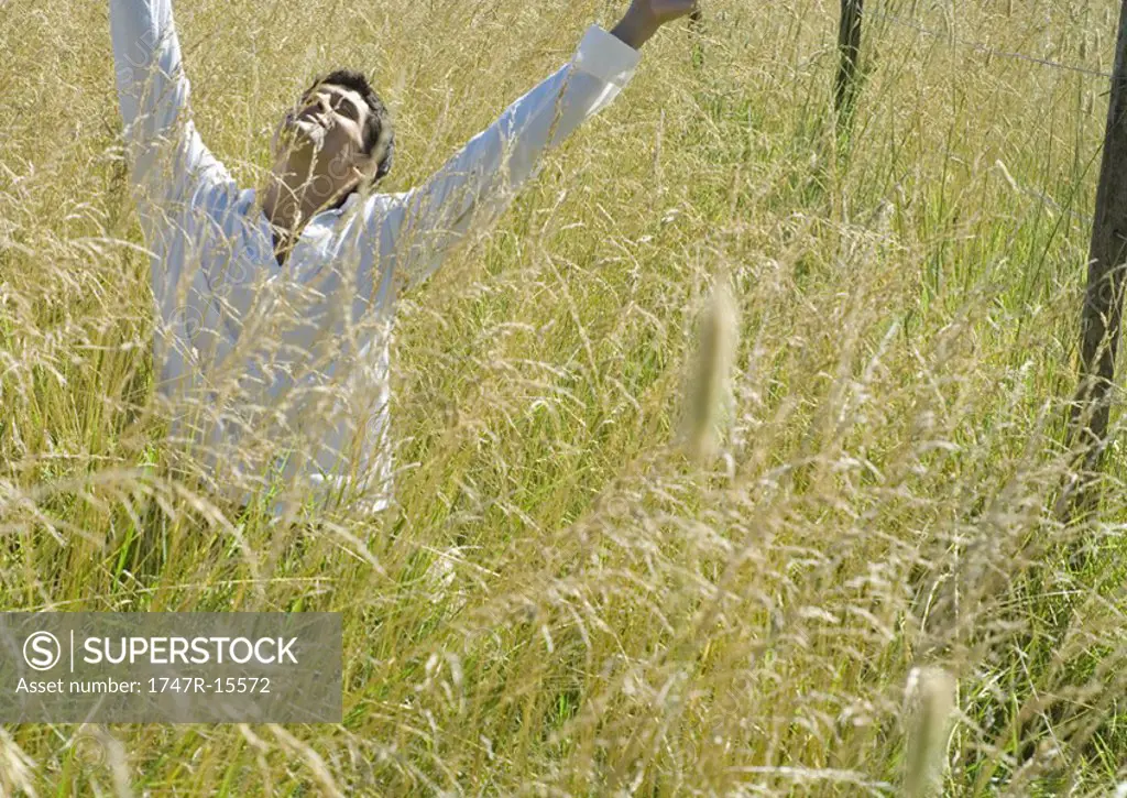 Man in field, arms raised and head back