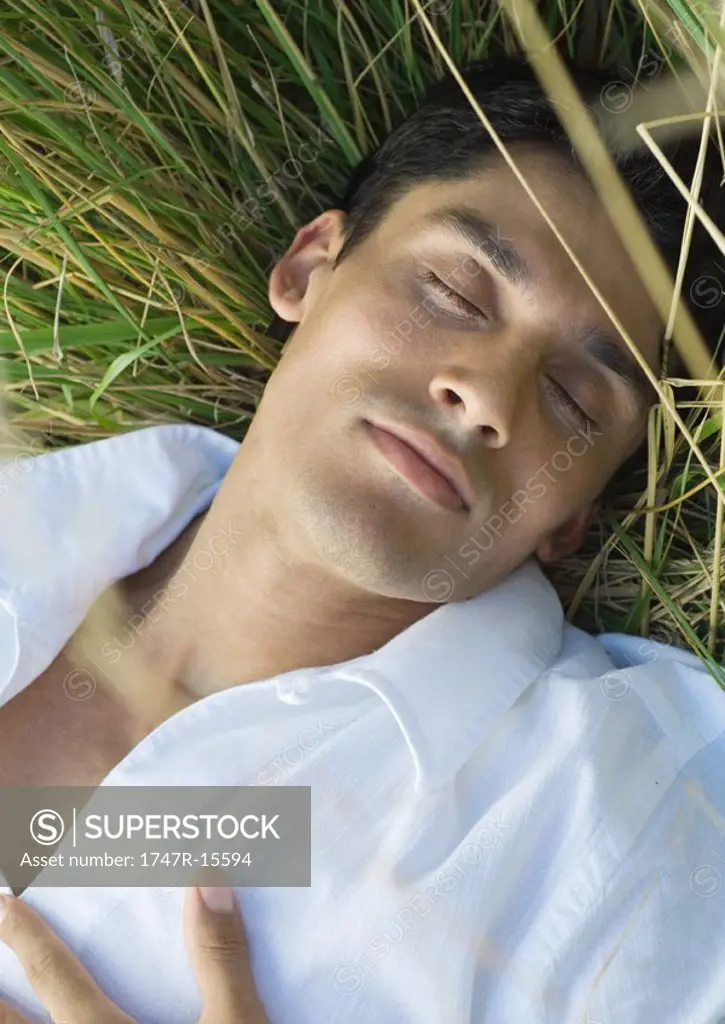 Man sleeping in tall grass, close-up