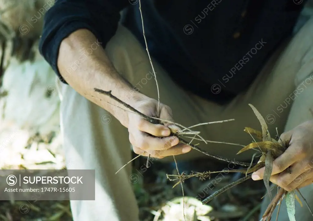 Man holding handful of twigs and leaves, cropped view