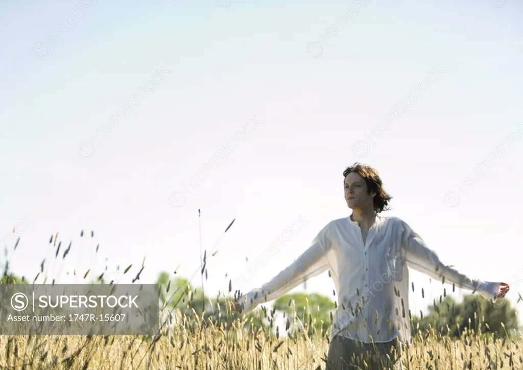 Man standing in field with arms out