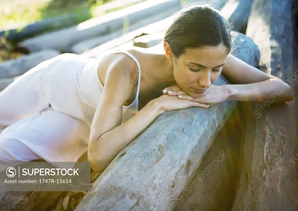 Woman reclining on pile of logs