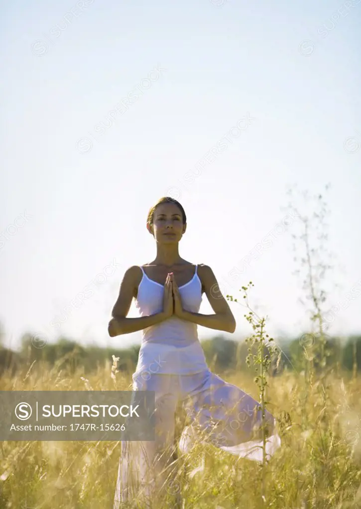 Woman standing in prayer position in field