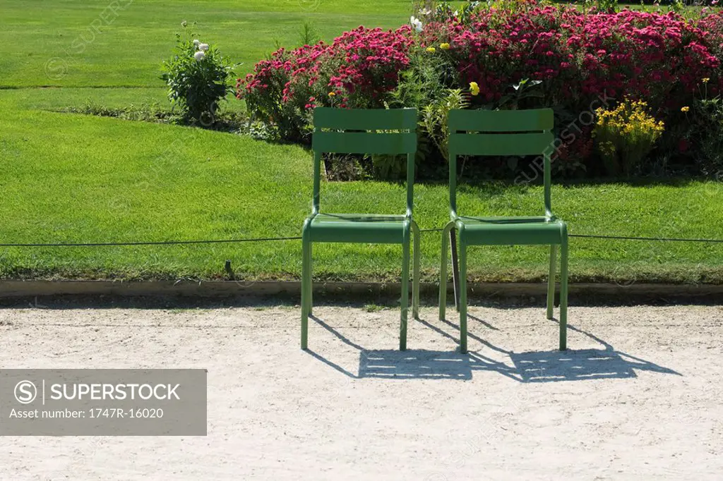 France, Paris, metal chairs set side by side in park