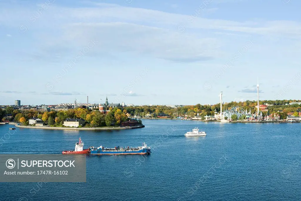 Sweden, Stockholm, Lake Malaren, tugboat pushing barge, city in background