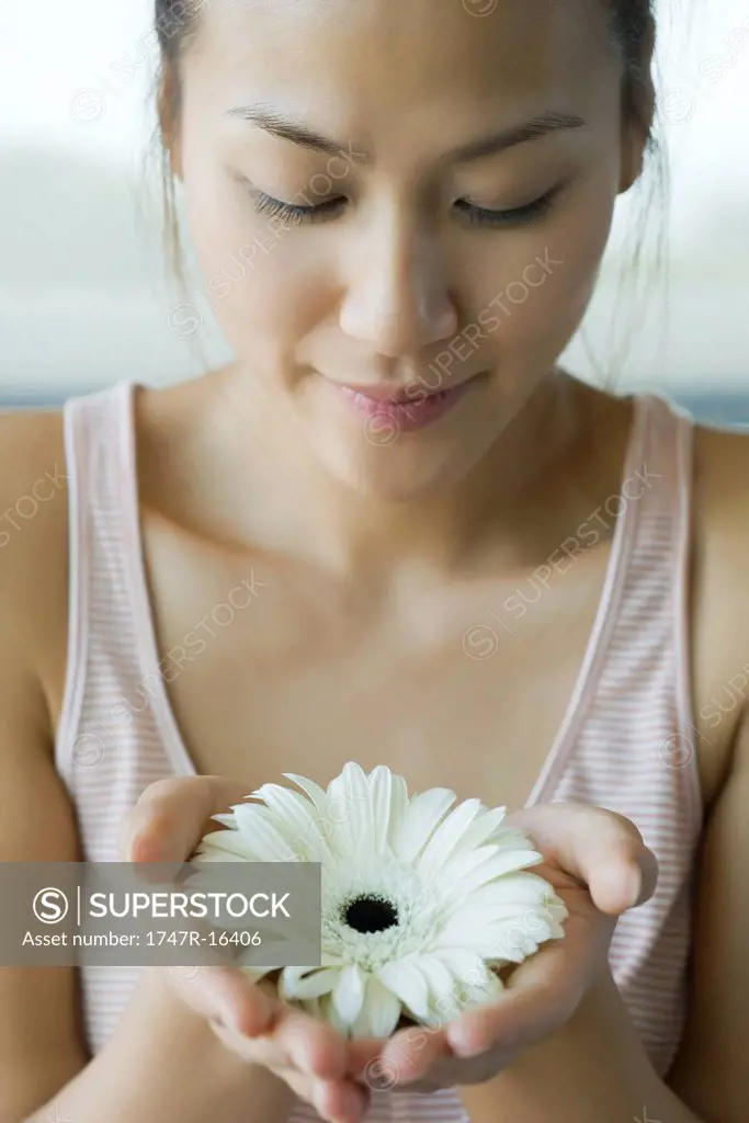Young woman holding gerbera daisy, portrait