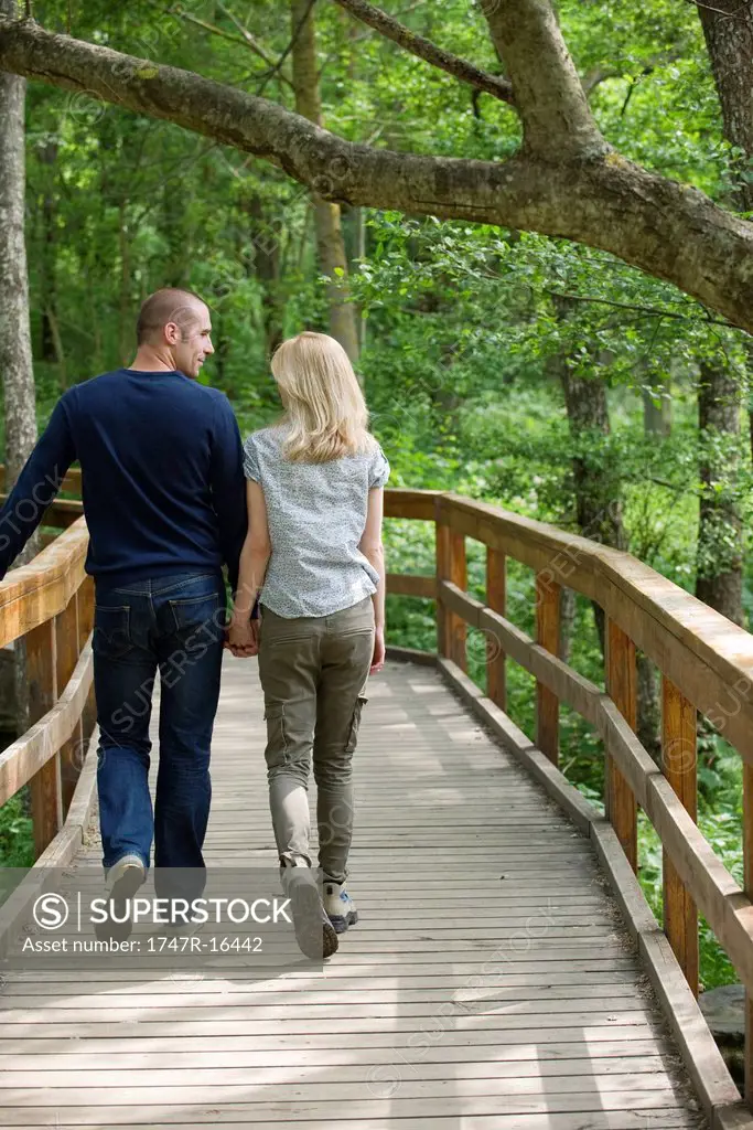 Couple walking on boardwalk in woods