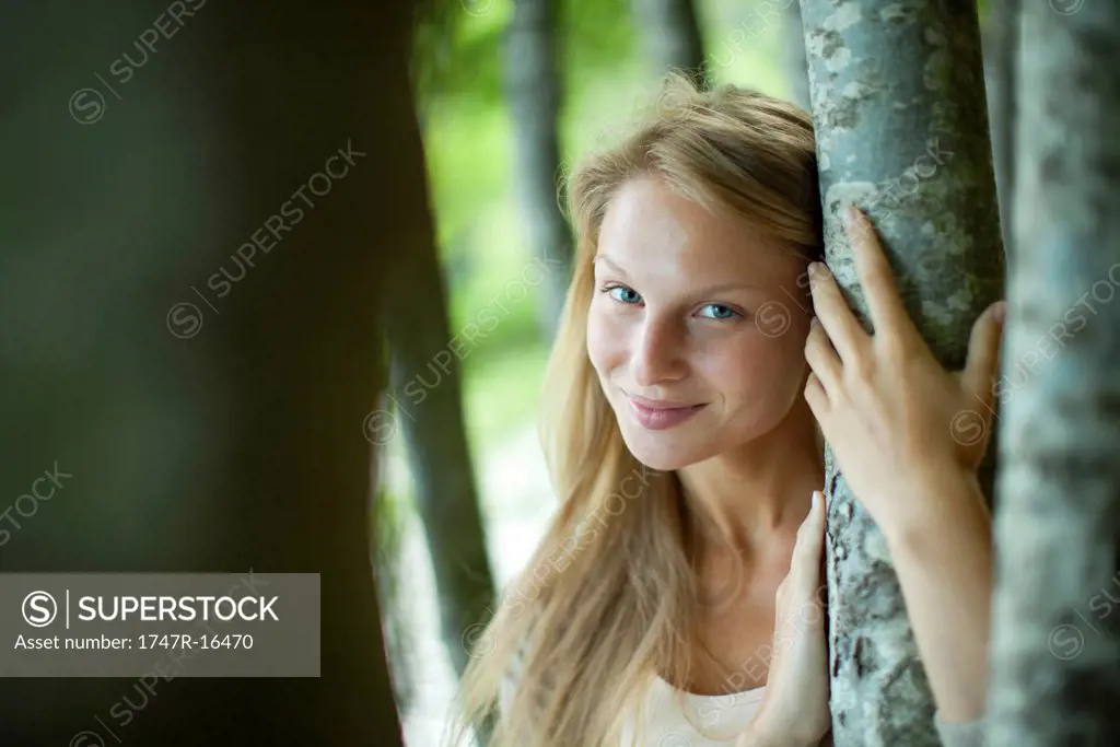 Woman leaning against tree trunk, portrait