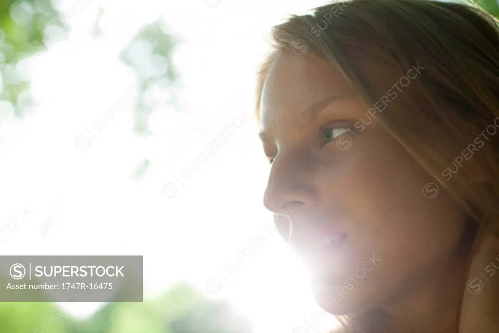 Young woman outdoors, looking away in thought