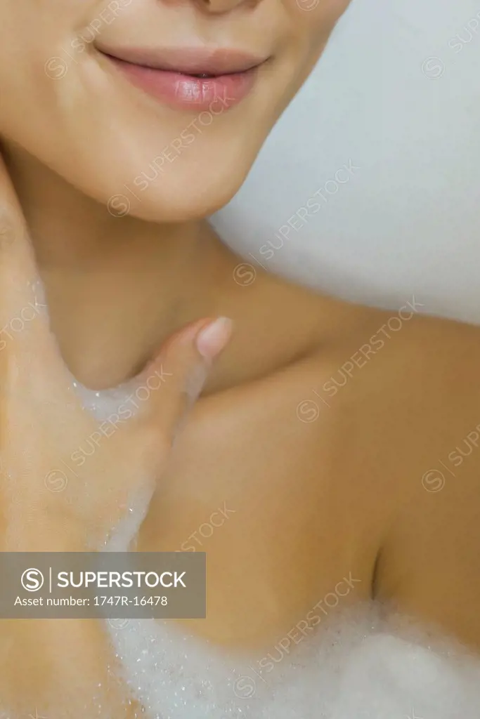 Woman soaking in bubble bath, cropped