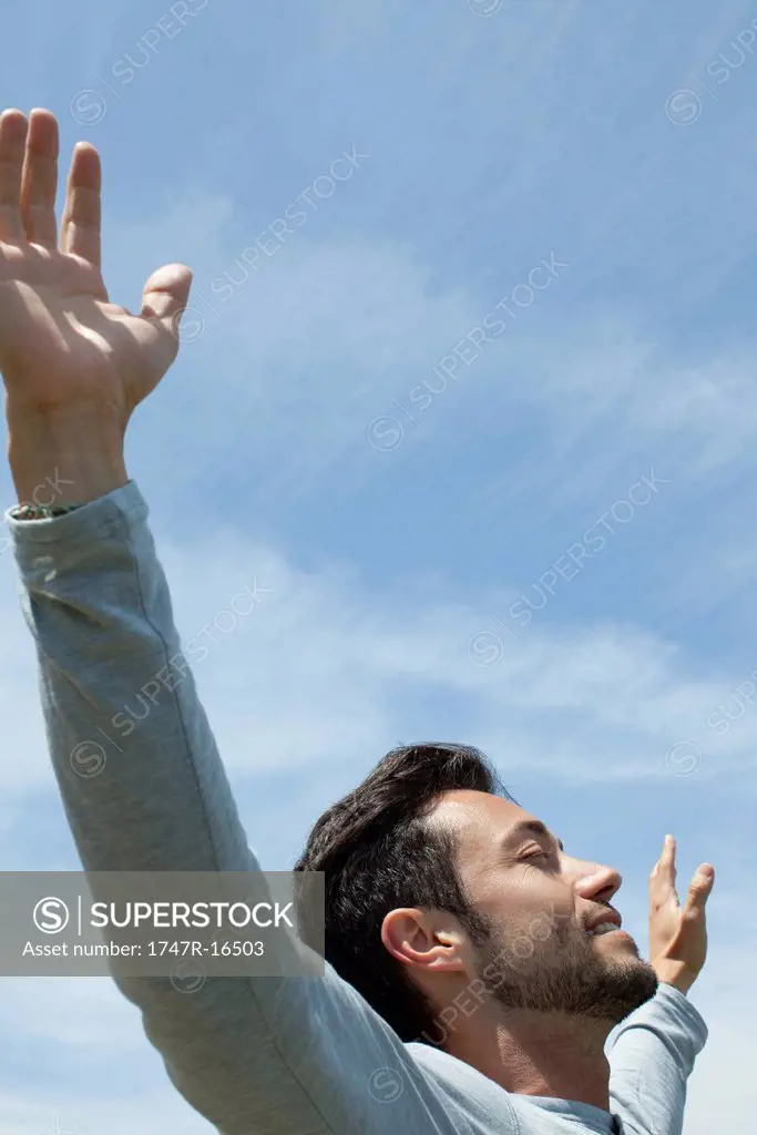 Man in outdoors with arms outstretched and eyes closed